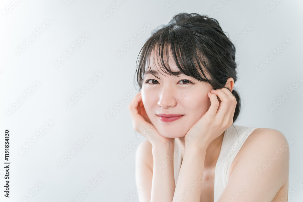 頬杖をしながら笑う若い日本人女性(美容・美白・エステ・スキンケアイメージ)
