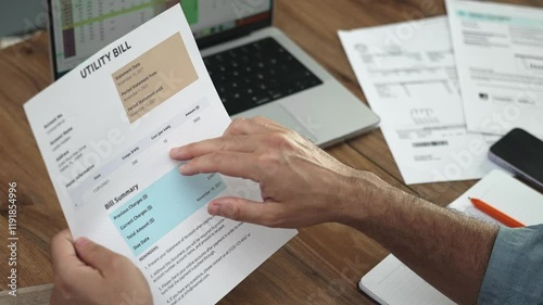 Businessman points at detailed text on utility bill transcribing into laptop, male accountant scrutinizes documents pertaining to household services slow motion