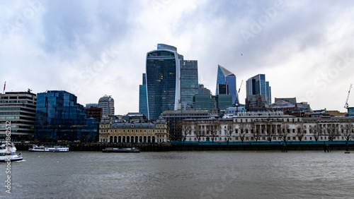 A vibrant cityscape of London featuring the iconic Walkie-Talkie building and other modern skyscrapers. The River Thames flows in the foreground
