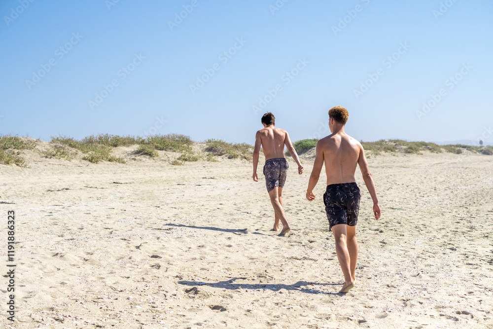 Two young people in swimwear strolling along the beach, exuding tranquility and relaxation, enjoying their vacation by the sea.