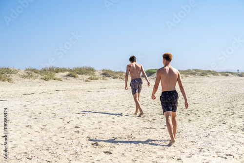 Obraz na płótnie Two young people in swimwear strolling along the beach, exuding tranquility and relaxation, enjoying their vacation by the sea. w salonie