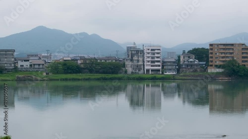 Cityscape of Inuyama, Japan, along the Kiso River. Some modern buildings line the riverbank in town. The quiet, misty atmosphere creates a peaceful Japanese aesthetic. 犬山,木曽川 photo