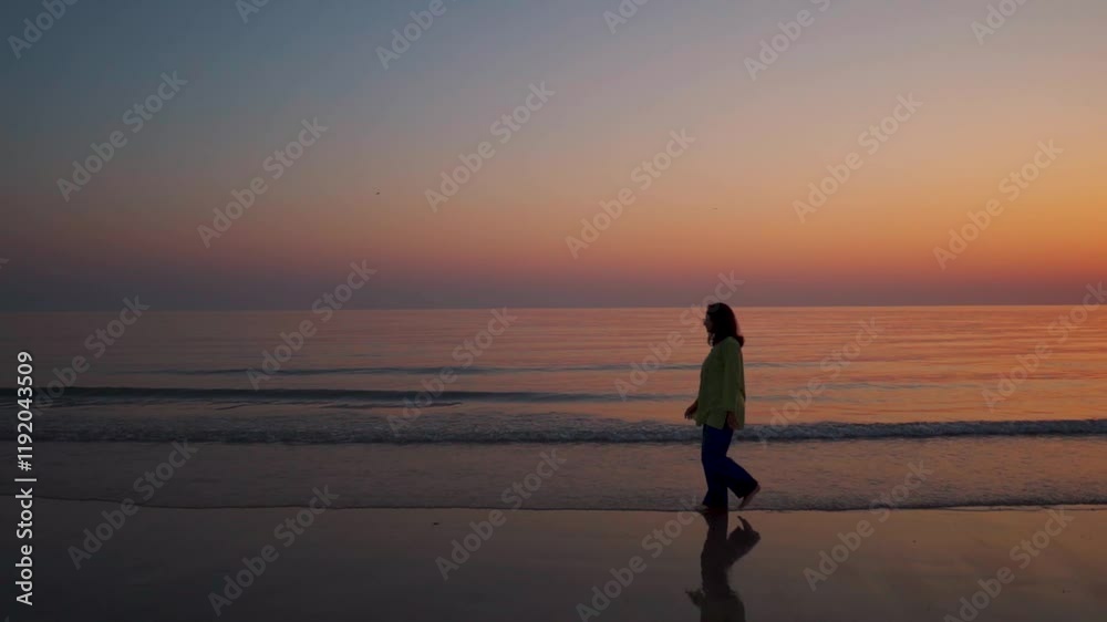 Silhouette of a girl walking at beach after sunset. Femininity concept. Tourist during summer vacation. Calm ocean waves at tropical beach. Silhouette of a girl walking at beach after sunset. Femininity concept. Tourist during summer vacation. Calm ocean waves at tropical beach.