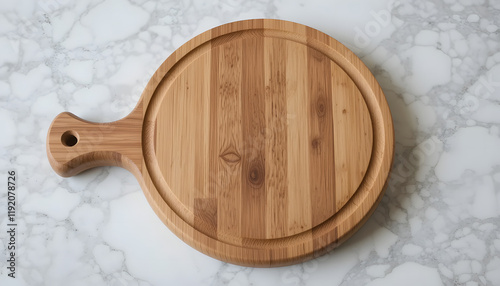 A round bamboo cutting board with a handle lies on a marble surface. photo