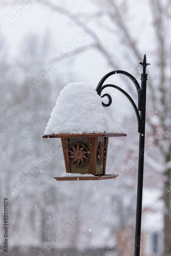 Snow covered birdfeeder on black iron hook