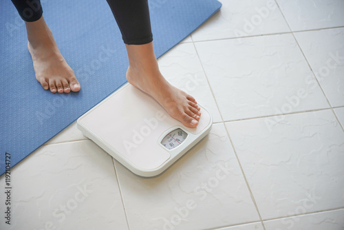 Asian woman in sportswear standing weighing after workout