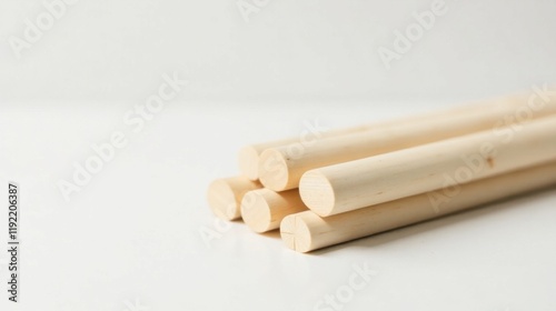 Smooth, Light-Colored Wooden Dowels Arranged in a Neat Stack on a Plain White Surface