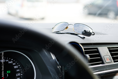 Sunglasses on the dashboard of a modern car. Selective focus.
