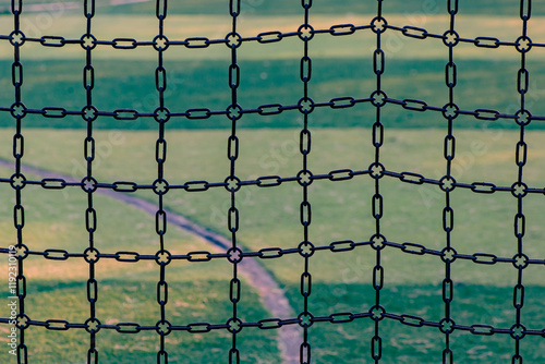 The safety fence made of iron chains around the sports field and the lawn inside the sports field