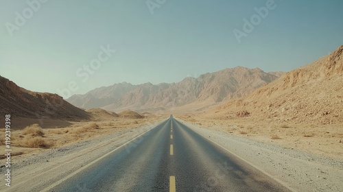 Empty highway through a rocky desert landscape, with towering red cliffs in the distance under a clear sky.