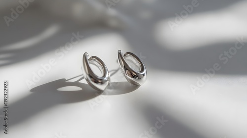 Elegant silver earrings displayed on soft surface minimalistic style natural lighting close-up view