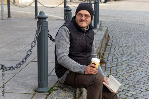 Obraz na płótnie A man reading a book outdoors in an autumn city. w salonie