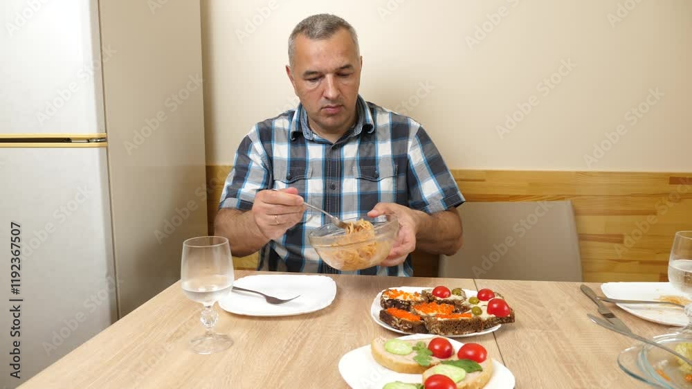 A man is eating spaghetti while sitting at the table. A man is eating spaghetti while sitting at the table.