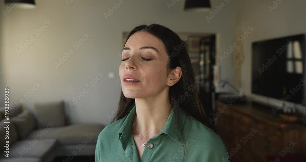 Close up beautiful young woman stand alone in contemporary living room with her eyes closed, breath fresh conditioner air, smile, enjoy freshness inside during summer day. Climate control, stress-free Close up beautiful young woman stand alone in contemporary living room with her eyes closed, breath fresh conditioner air, smile, enjoy freshness inside during summer day. Climate control, stress-free