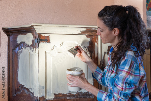 Woman restoring antique wooden furniture using paint and brush