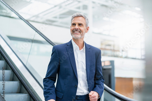 Smiling gray haired businessman on escalator in airport photo