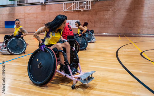 Woman sitting in wheelchair and chasing opponent at sports center photo