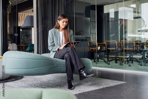 Business woman sitting on sofa with tablet PC at office
