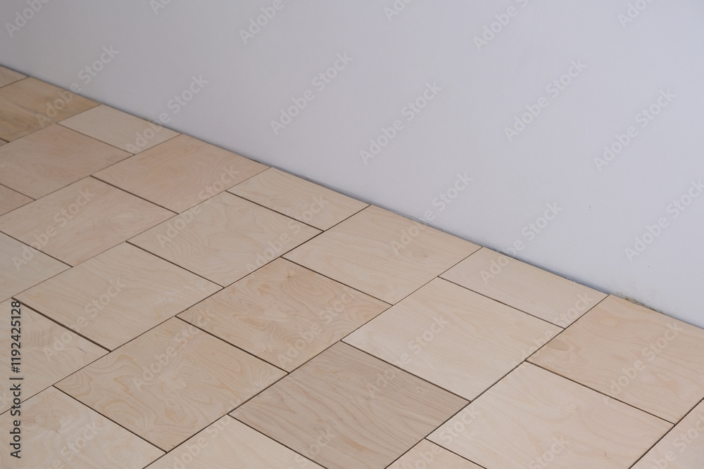 Fototapeta premium Base for floor coverings, parquet or laminate. Laying of the rough floor, a substrate of thick plywood in the form of squares with technological gaps. Repair work. Apartment renovation, building