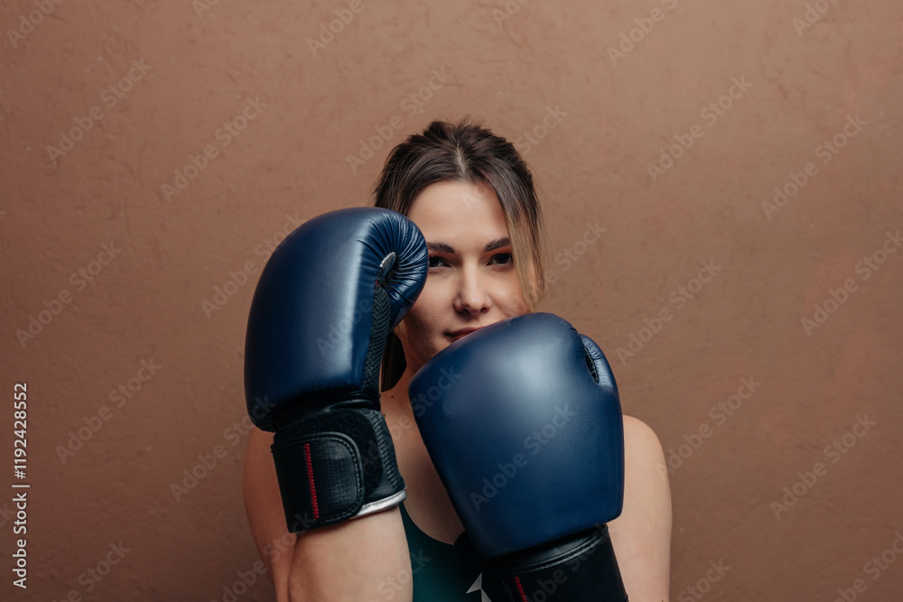 Woman in boxing gloves against brown background Woman in boxing gloves against brown background