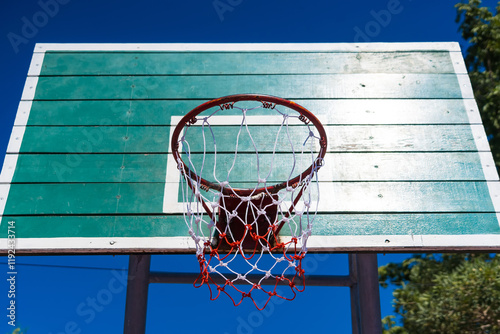 Outdoor Basketball Hoop with Green Wooden Backboard and Blue Sky Background, Perfect for Recreational Sports and Exercise Enthusiasts