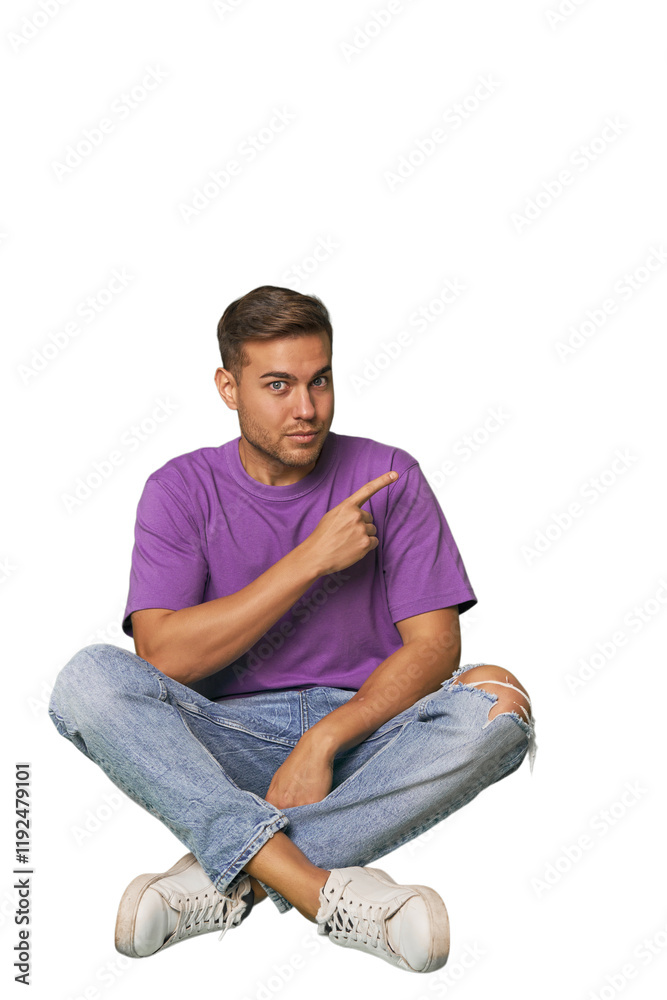 Casual man sitting on floor pointing to the side Casual man sitting on floor pointing to the side