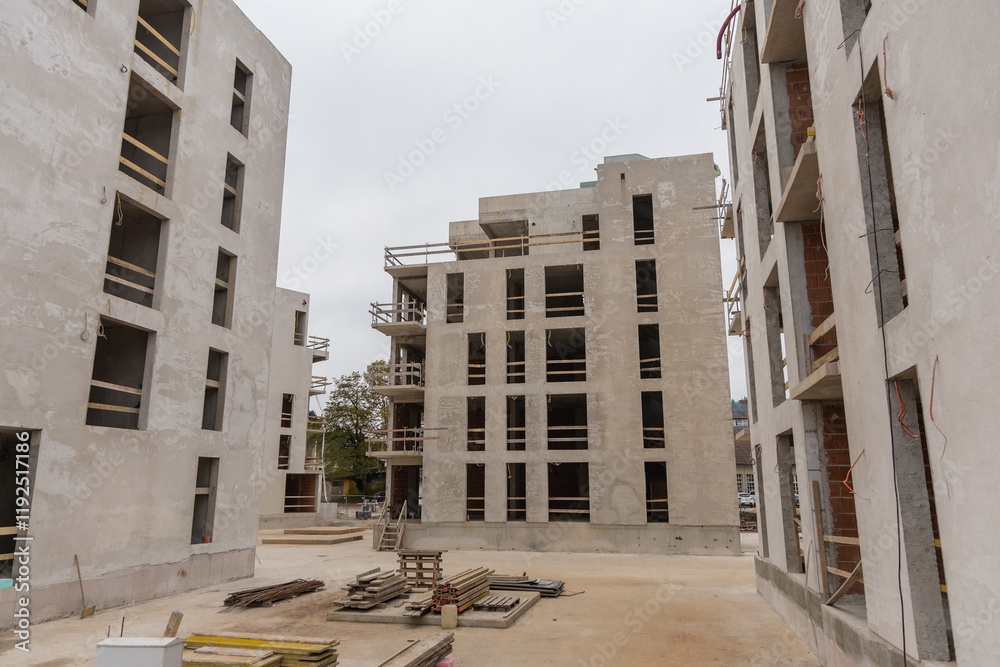 City blocks under construction. Typical construction site of modern housing made of concrete and red bricks. Multiple houses visible..