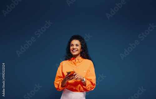 Happy young woman texting in vibrant orange and blue colorblocking outfit