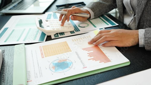 Young Asian accountant doing paperwork using laptop computer sitting in business office Make a financial report, analyze financial graphs or write tax forms.