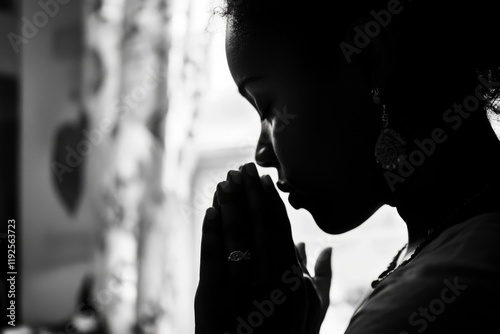 A woman in prayer, hands clasped together in devotion