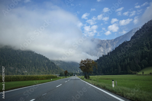 Scenic drive through the Austrian countryside under a cloudy sky with mountains in the background