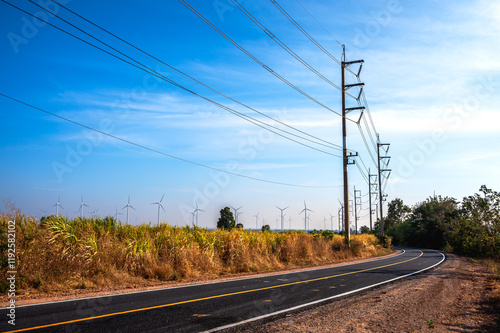 High voltage poles and pylons with group of wind turbines standing in field for sustainable energy  photo