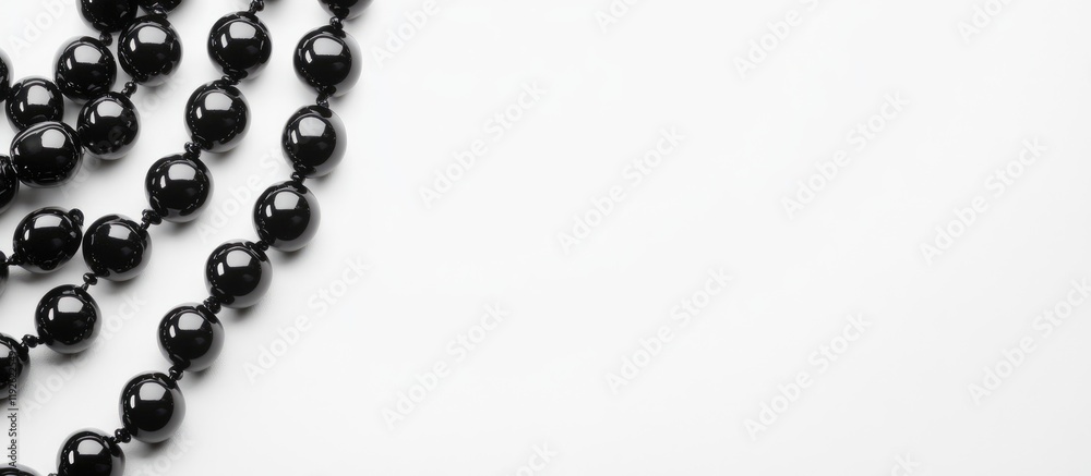 Elegant black smooth beads arranged on a white background with ample blank space for text or design elements. Ideal for jewelry marketing.