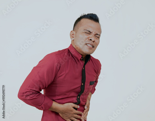 Stomach ache, pain and portrait of asian man on a white background with indigestion, hurt and injury. Healthcare, sick and isolated person holding abdomen for nausea, belly problems and tummy cramps. photo