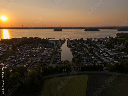 Aerial view of lakeside houses at sunset with wind turbines in the background. Nunspeet, Netherlands photo