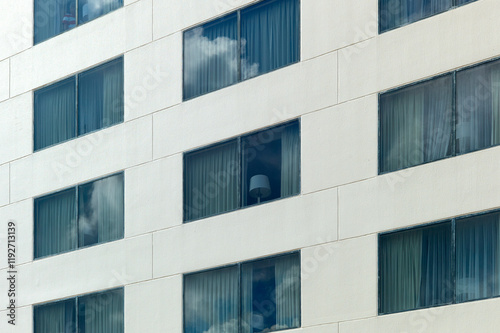 Exterior view of a modern building facade with a pattern of windows, some reflecting the sky and one partially open, New Orleans, USA photo