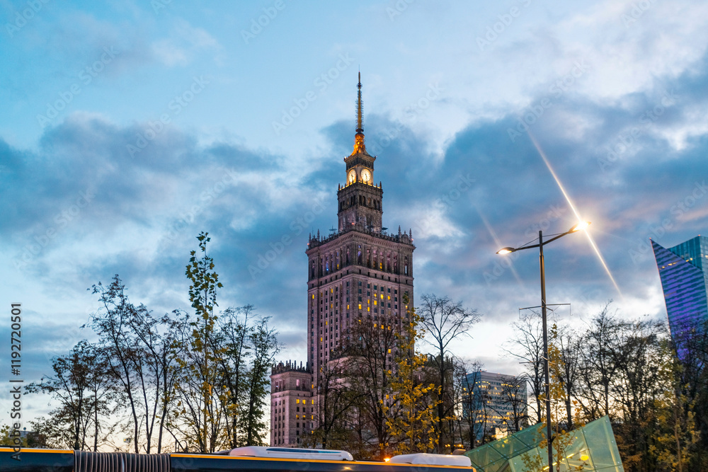 Evening view of Palace of Culture and Science tower lit up against a dusk sky with city lights and trees, Warsaw, Poland Evening view of Palace of Culture and Science tower lit up against a dusk sky with city lights and trees, Warsaw, Poland