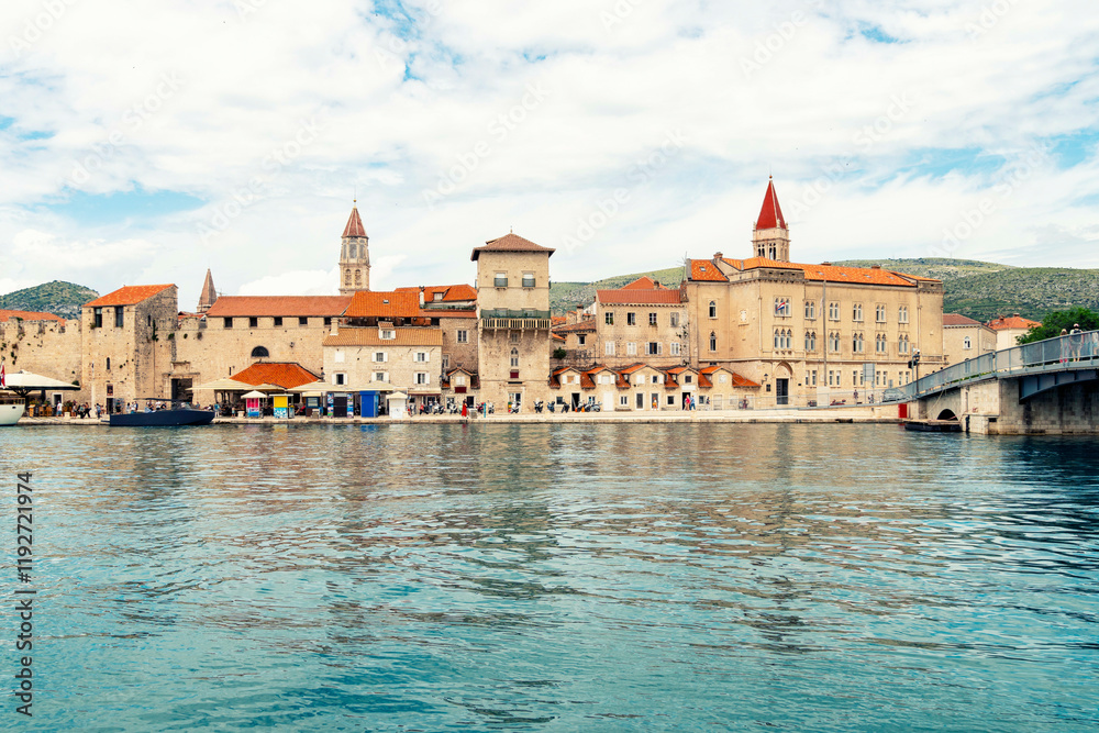 Panoramic view of the coastal town of Trogir with historic stone buildings by the sea under a partly cloudy sky, Croatia Panoramic view of the coastal town of Trogir with historic stone buildings by the sea under a partly cloudy sky, Croatia