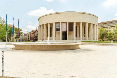 Circular modern building  of Croatian Association of Fine Artists with columns in an urban green space under a blue sky, Zagreb, Croatia photo