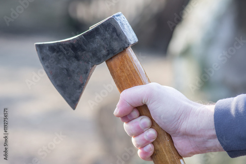 An axe in a man's hands. A tool for chopping and chiseling. A cold weapon.