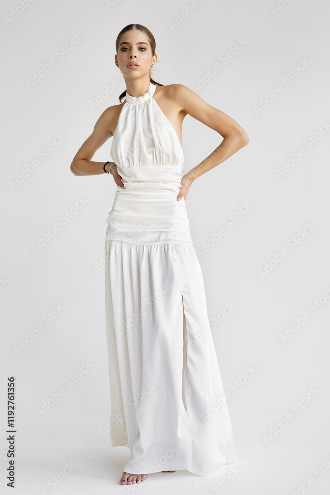 Young fashion model posing in long stylish white dress against isolated white background in studio. Woman beauty and grace Young fashion model posing in long stylish white dress against isolated white background in studio. Woman beauty and grace