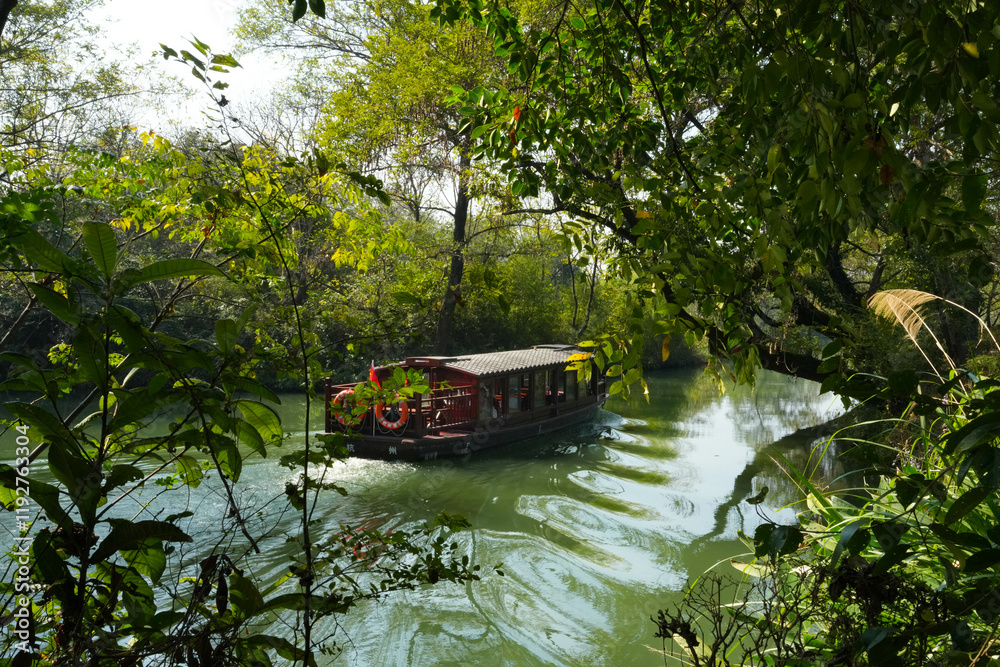 Fototapeta premium A ferry taxi glides through the serene waters of the national wetland park in Hangzhou City.