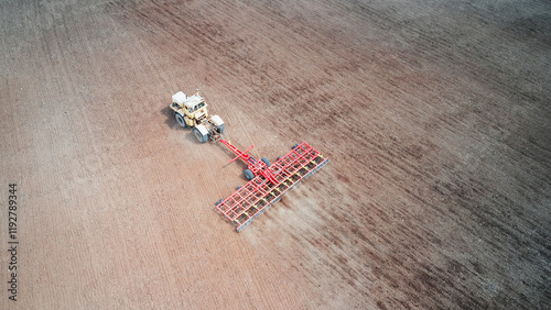 A single tractor with a trailed combination machine cultivates arable land before sowing crop seeds. Drone footage.