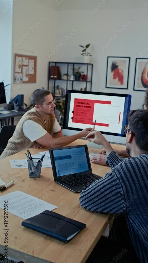 Vertical shot of two men listening to their colleague giving presentation during business meeting in modern open space office