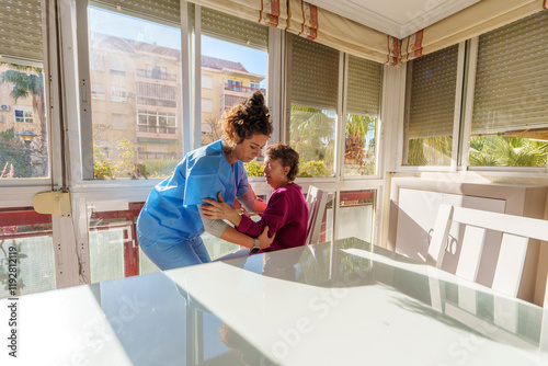Papier peint Young nurse assisting elderly woman in getting up from chair, surrounded by a br