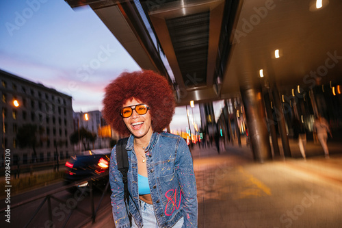 Joyful African descendent woman with afro hair under city lights photo