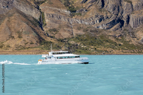 A large boat sailing on a blue water lake near mountains. Patagonia. Transportation. Tourism.