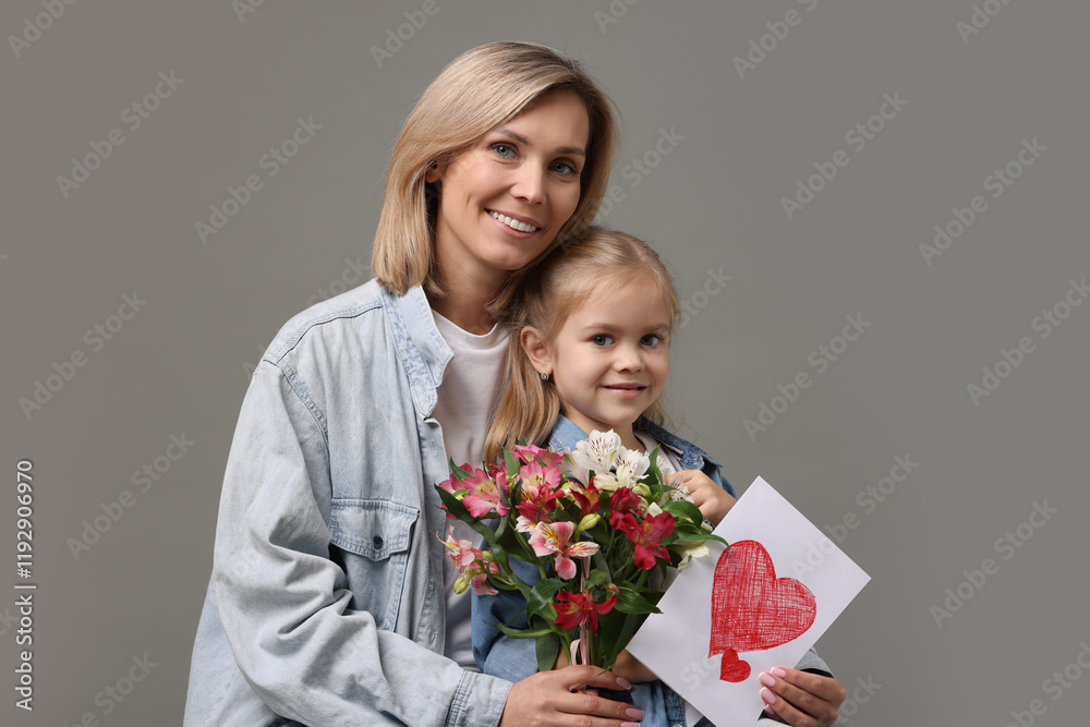 Happy woman with her daughter, bouquet of alstroemeria flowers and greeting card on gray background. Mother's Day celebration Happy woman with her daughter, bouquet of alstroemeria flowers and greeting card on gray background. Mother's Day celebration