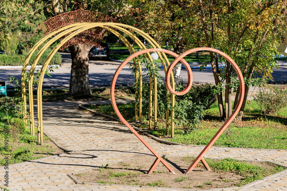 Heart-shaped sculpture in tranquil park with wooden arch Heart-shaped sculpture in tranquil park with wooden arch