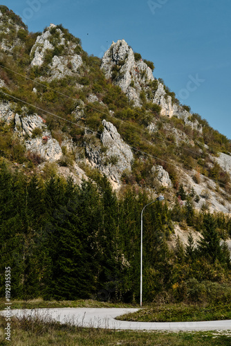 A winding paved mountain road in golden autumn season. Beautiful nature of southwestern Serbia. Steep cliffs with eagles are visible behind. photo